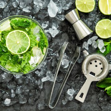 A refreshing mojito cocktail with lime, mint, and ice on a dark surface.