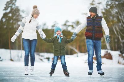A family ice skating outdoors on a winter day.