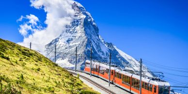Scenic train near snowy mountain.