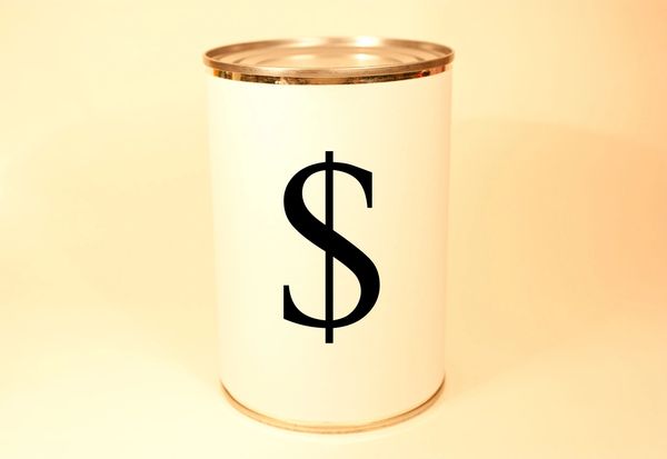 A plain can with a dollar sign on it against a beige background.