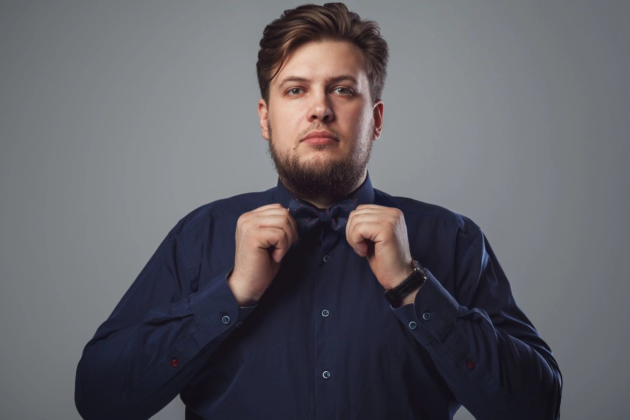 Man adjusting his bow tie in a blue shirt.