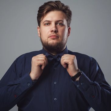 Man adjusting his bow tie wearing a dark shirt.