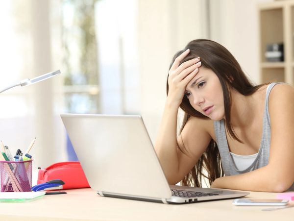 Woman looking stressed while using a laptop.