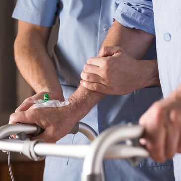 Nurse assisting a patient walk with a walker and an IV in his right hand.