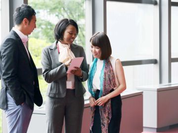 Three professionals engage in discussion while reviewing a document in a bright office space.