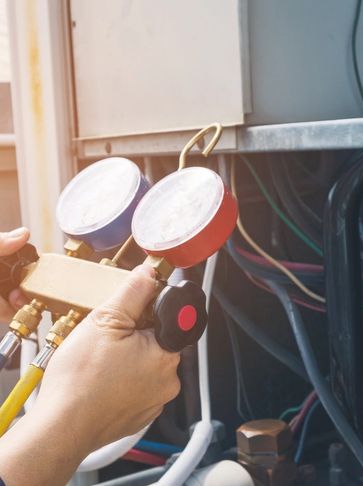 H.V.A.C. technician using refrigerant gauges to diagnose/troubleshoot an AC system.