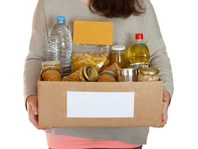 Lady holding box of donated non-perishable food.