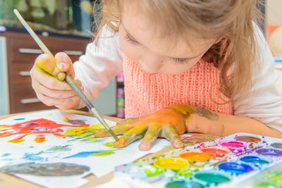 Little girl playing and coloring with the water colors.