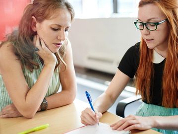 Two women taking ntoes