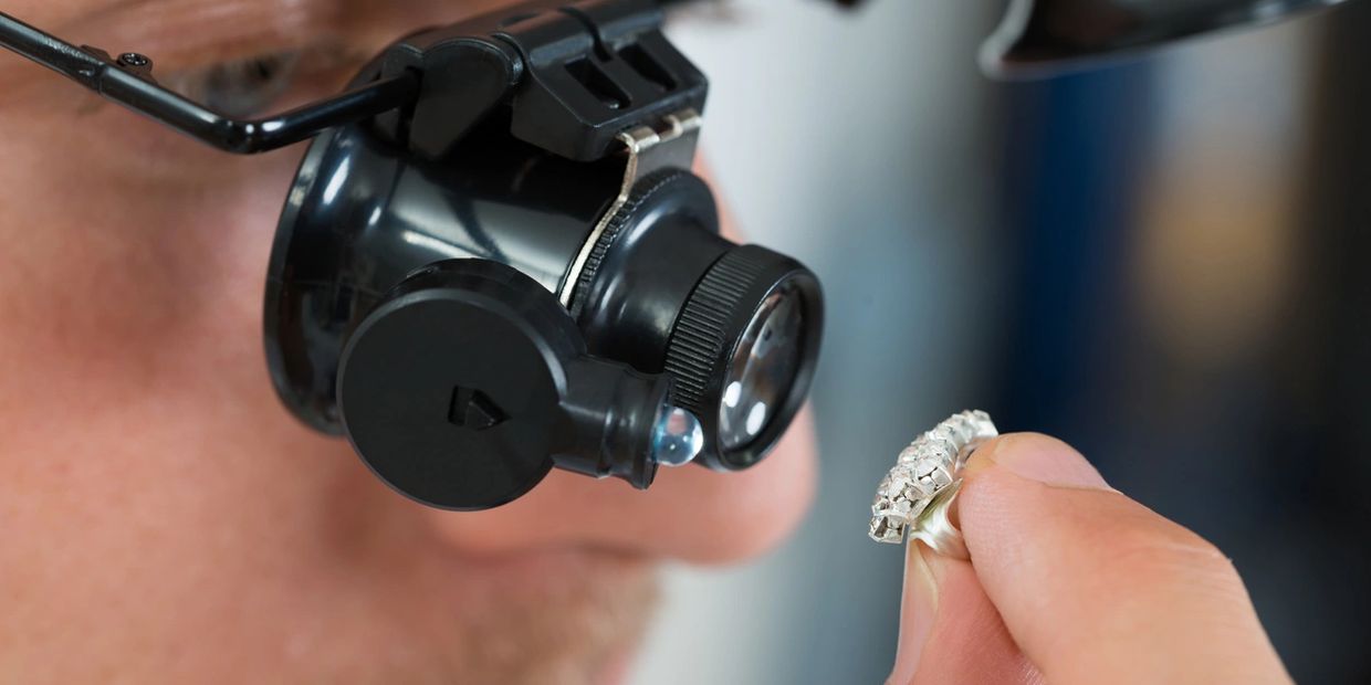 Expert inspecting a diamond ring with magnifying glasses.