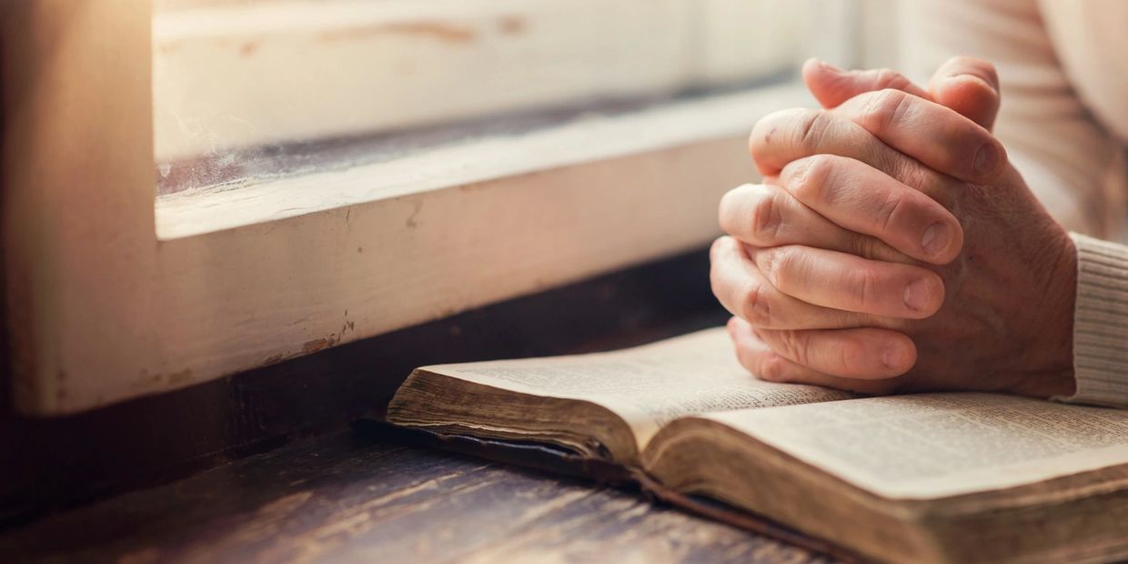 Praying over Bible by a window