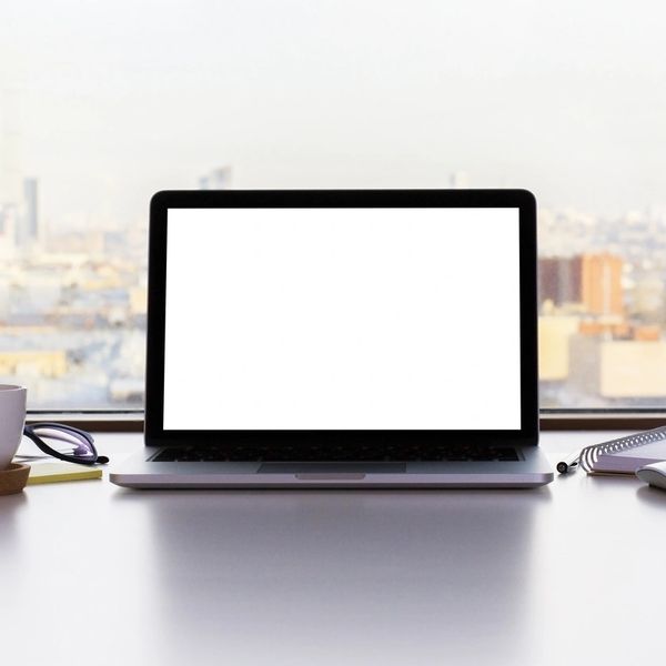 A open laptop with a white blank screen with a city skyline in the background