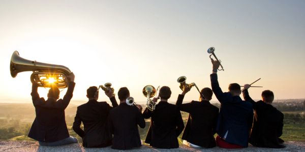 A group of musicians holding brass instruments at sunset.