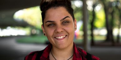 Youth faces the camera smiling. Short cut, straight, black hair, wears a red & black shirt.