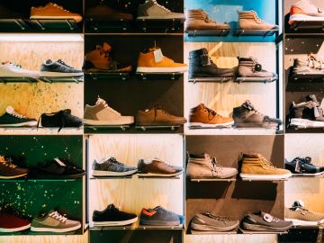 Various shoes displayed on shelves in a store under warm lighting.