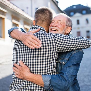 Senior man hugging adult son in street