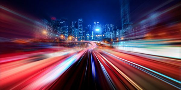 Timelapsed photo of cars traveling on road with city skyline in background.