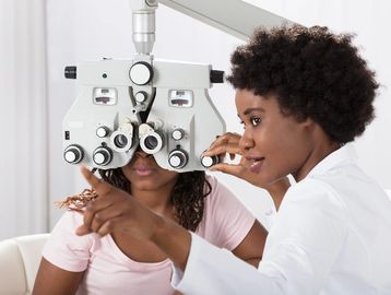 Eye doctor adjusting equipment for a patient's eye exam.