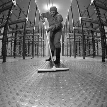 Person cleaning a large industrial floor with a mop.