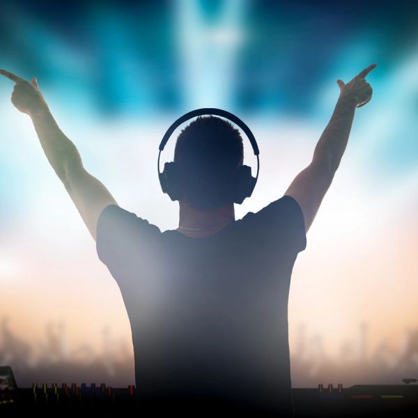 DJ with headphones raising hands at a party.