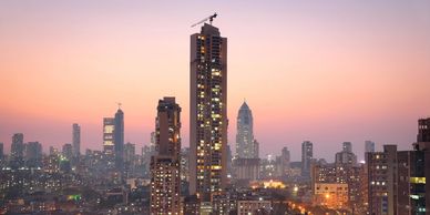City skyline at sunset with tall illuminated buildings.