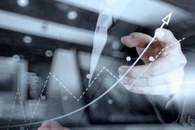 Businessman pointing at a rising graph showing growth.