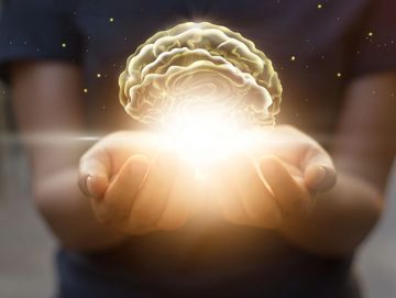 An image of a child's hands holding an illuminating brain. 