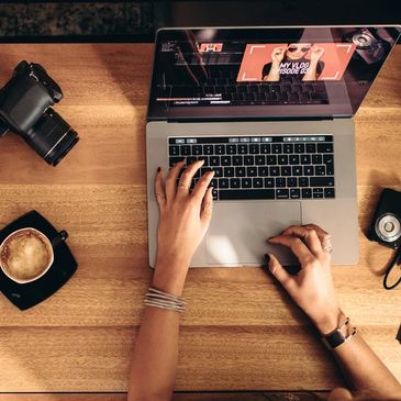 Hands typing creative content on a laptop at a desk with neighbouring coffee