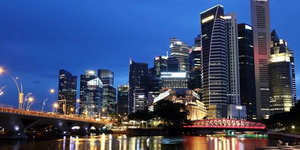 Night view of a city's illuminated skyline with a bridge over water.