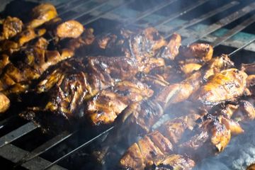 Grilled marinated chicken cooking over hot coals on a barbecue grill.