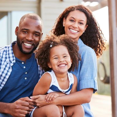 Happy family of three smiling outdoors together.