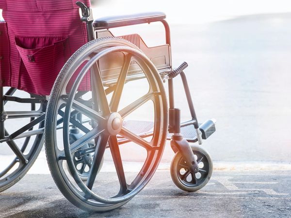 Close-up of an empty wheelchair on a sunlit floor.