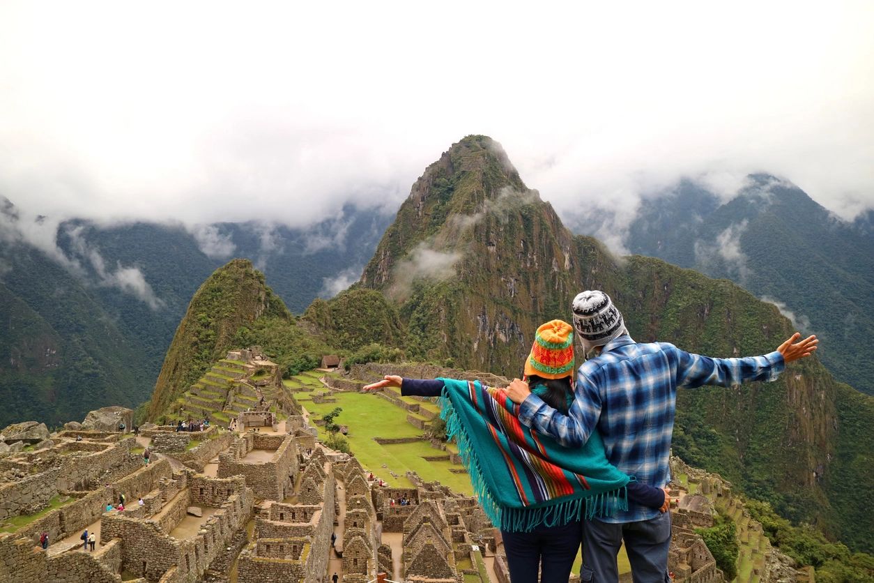Couple enjoying the view at Machu Picchu with arms outstretched.