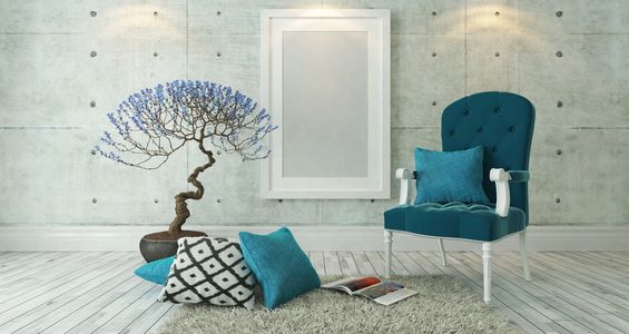 a minimalist room in concrete and grey, with a teal chair, pillows and a small tree