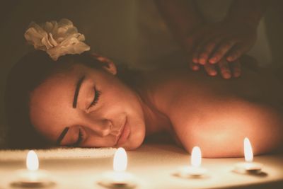 Woman enjoying a relaxing massage with candles and a flower in her hair.