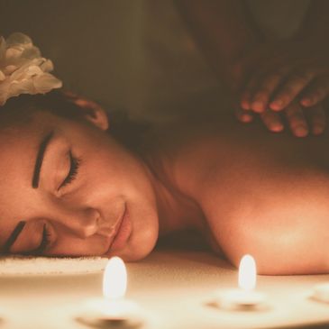 Woman enjoying a relaxing candlelit massage with a flower in her hair.