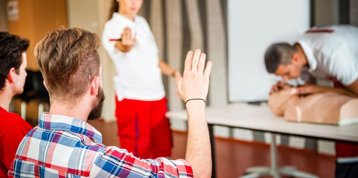 A person raising hand on the class during a CPR demonstration.