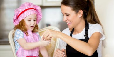 A mother and daughter baking together, smiling and having fun.