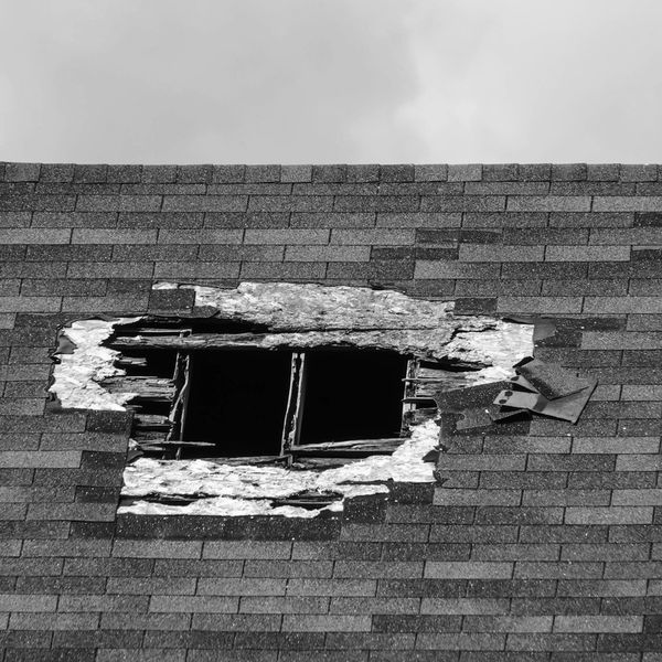 Damaged roof with a large broken section revealing wooden beams.