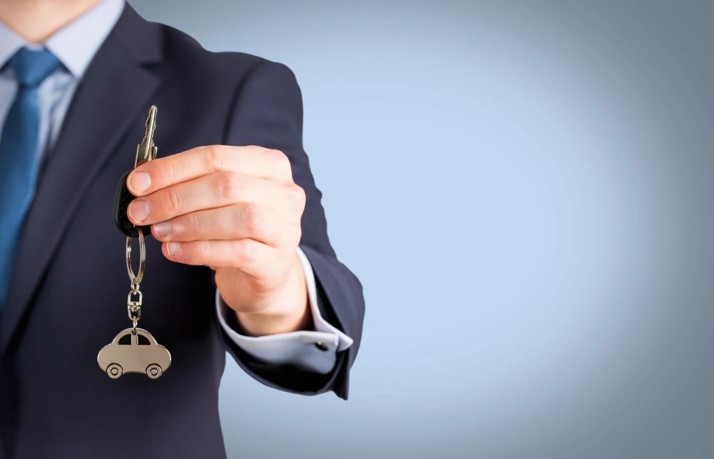 Person holding a car key with keychain.