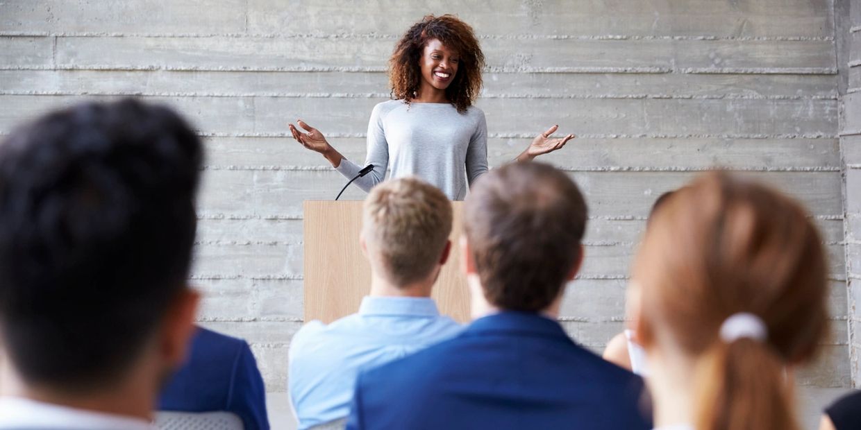 a woman giving a speech in front of a group of people