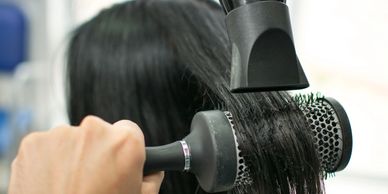 Blow drying and brushing hair in a salon.