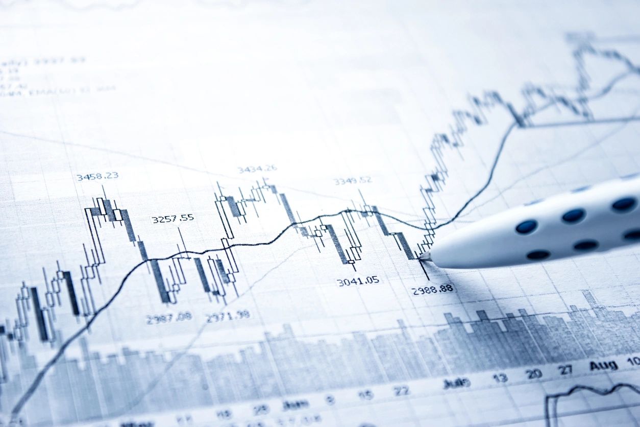 Pen points to a doji candle stick on a paper printout of a candle stick chart.