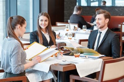 Three business people reviewing menus at a restaurant.