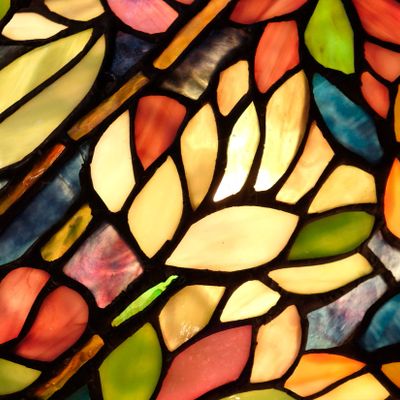 Colorful stained glass window with floral and leaf patterns.
