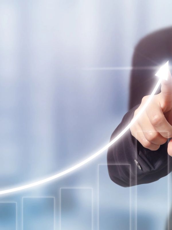 Hand pointing at rising arrow on a digital graph.
