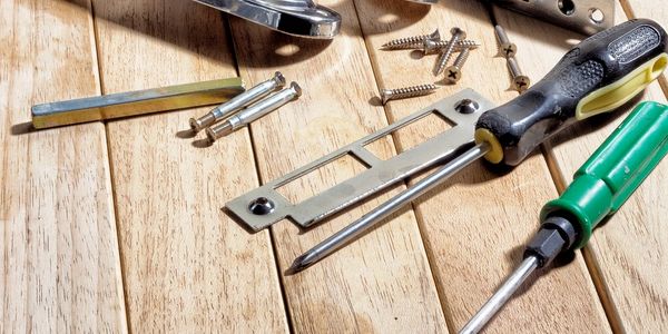 Various tools and screws arranged on a wooden surface.