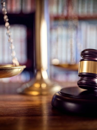 Gavel and scales of justice on a wooden desk in a law office.