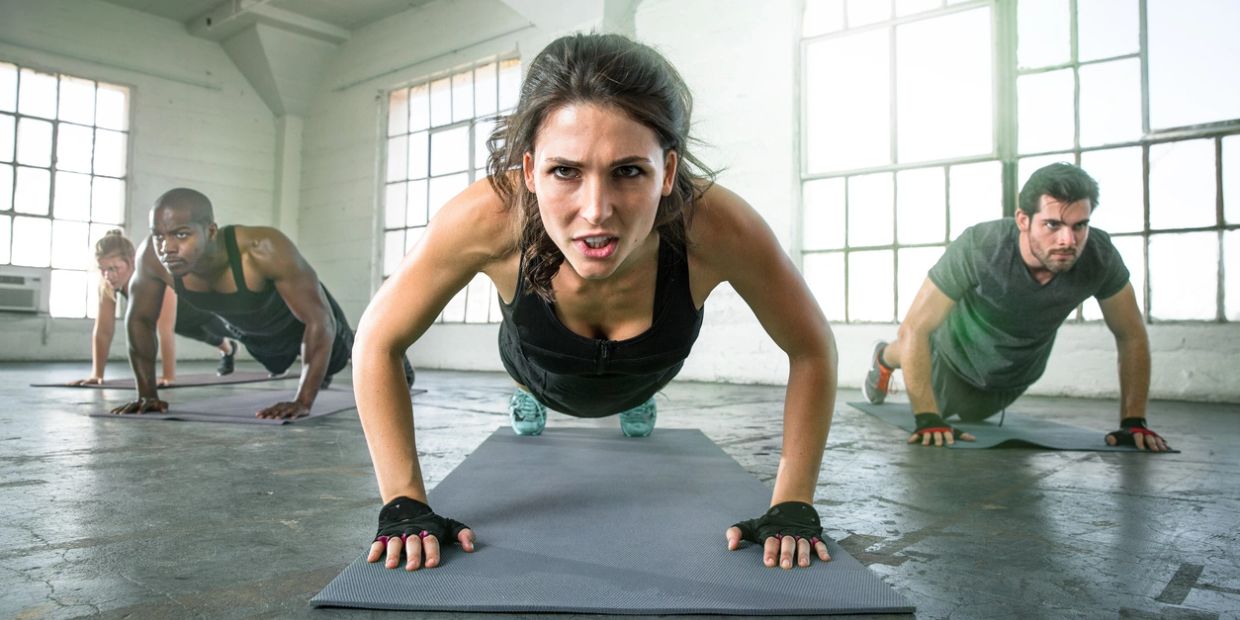Focused group doing push-ups in a bright gym.