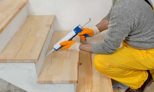 Contractor applying stair adhesive on staircase.